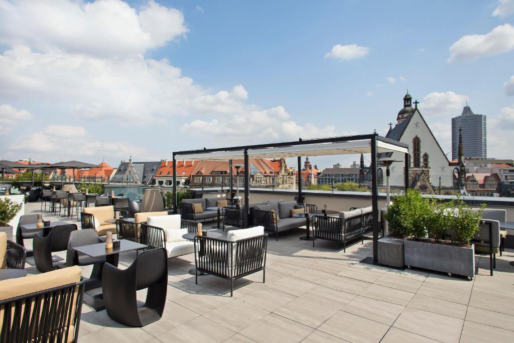 a patio with tables and chairs on a roof at INNSiDE by Meliá Leipzig in Leipzig