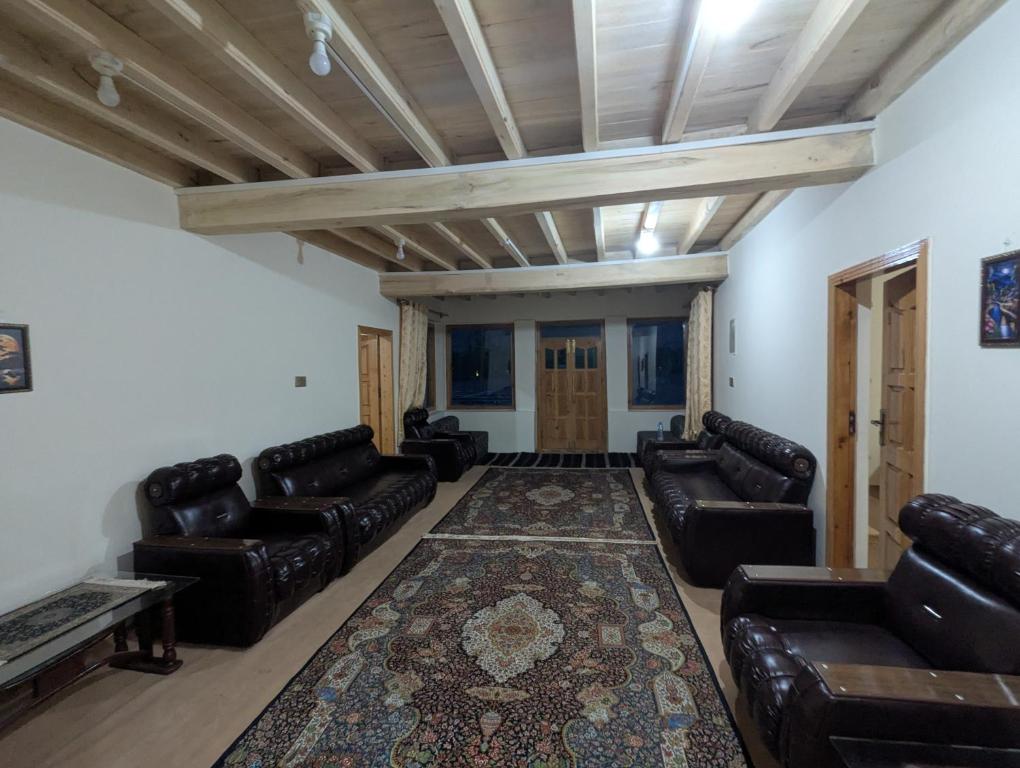 a living room with leather couches and a rug at Passu Didargah Resort in Pasu