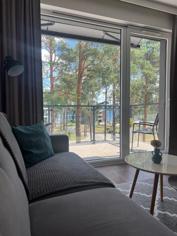 a living room with a bed and a glass window at Sosnowe Apartamenty - Marina in Augustów