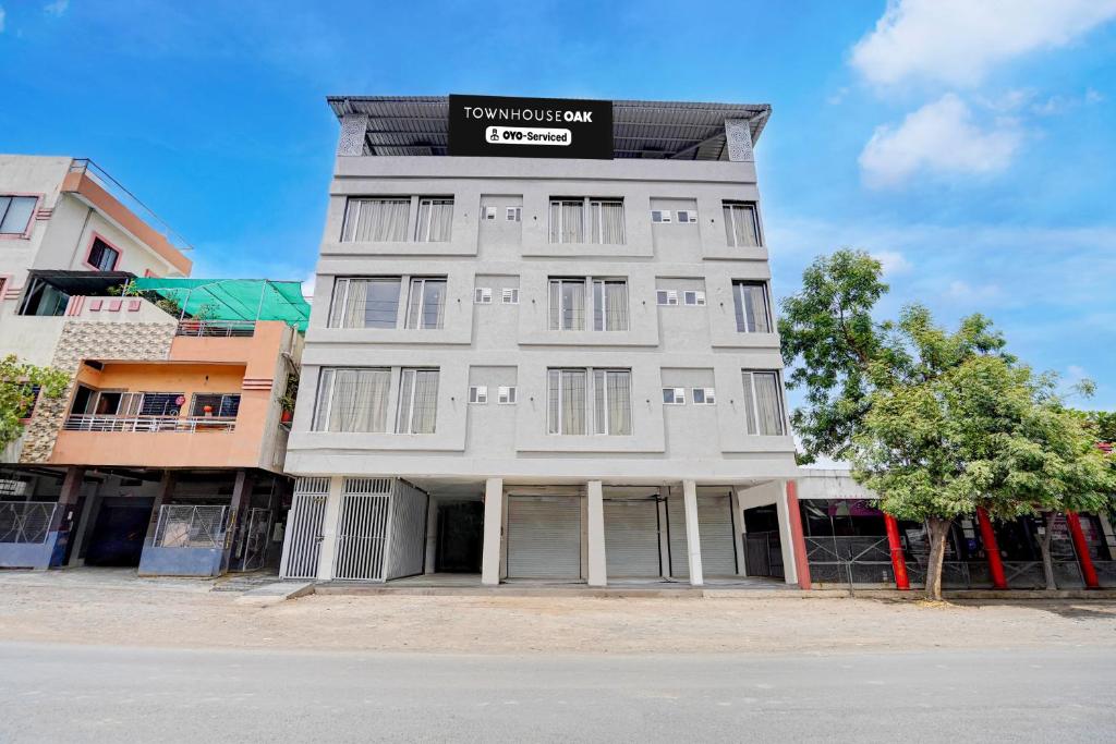 a tall white building with a sign on it at Townhouse Oak Ujjain Railway Station Formerly Kasliwal Inn in Ujjain