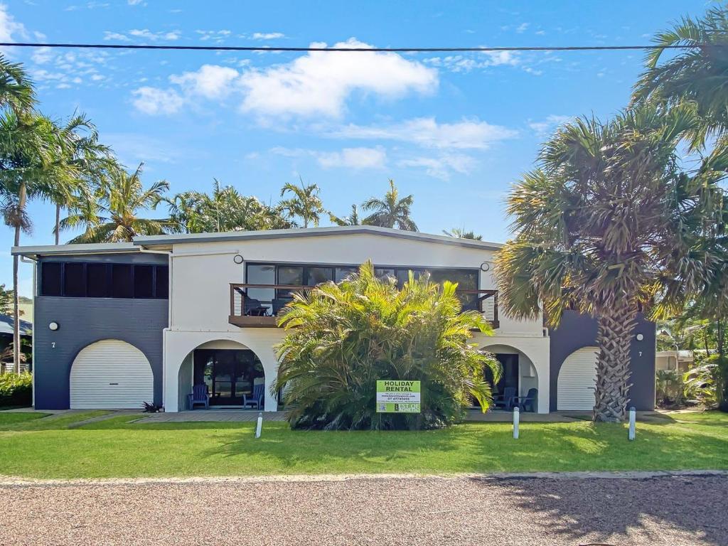 a white house with palm trees in front of it at Beachside Palms Unit 3 in Nelly Bay