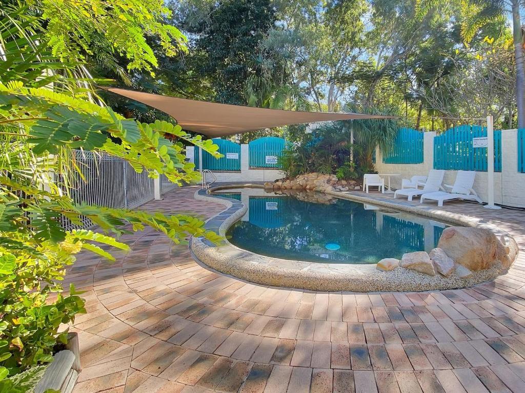 a swimming pool with a tan umbrella on a patio at Magnetic Reef Unit 2 in Arcadia