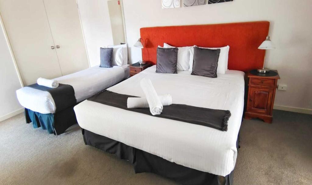 a hotel room with two beds and a red headboard at Suite 26 - Town Central - Walk To Cafes - Sleeps 3 in Margaret River Town