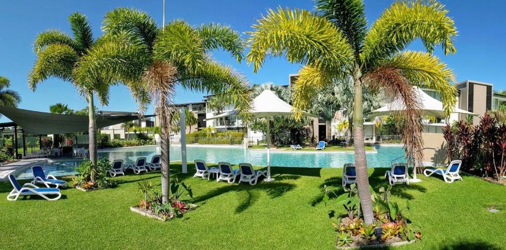 a resort with palm trees and chairs and a swimming pool at Blue on Blue Apartment 932 in Nelly Bay