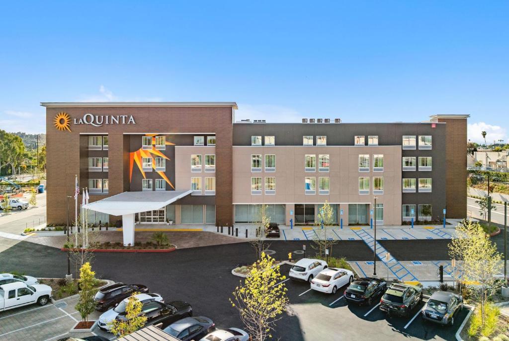 a hotel with cars parked in a parking lot at La Quinta Inn & Suites by Wyndham La Habra in La Habra