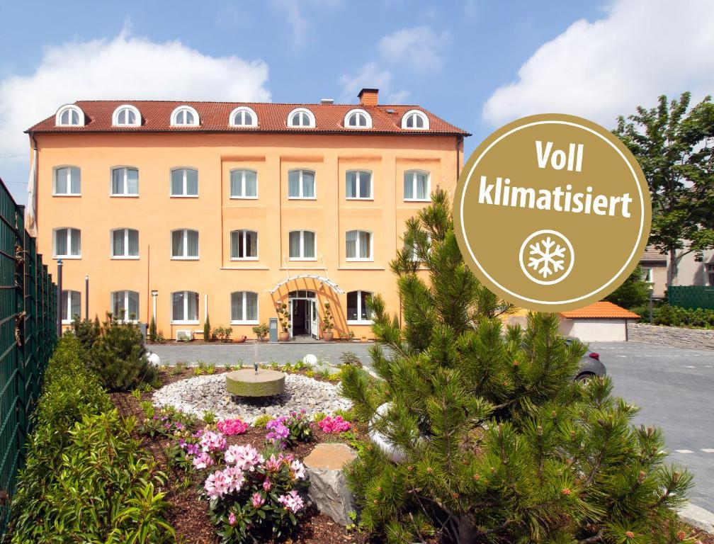 a building with a sign in front of a garden at Hotel Am Mühlenteich in Schwelm