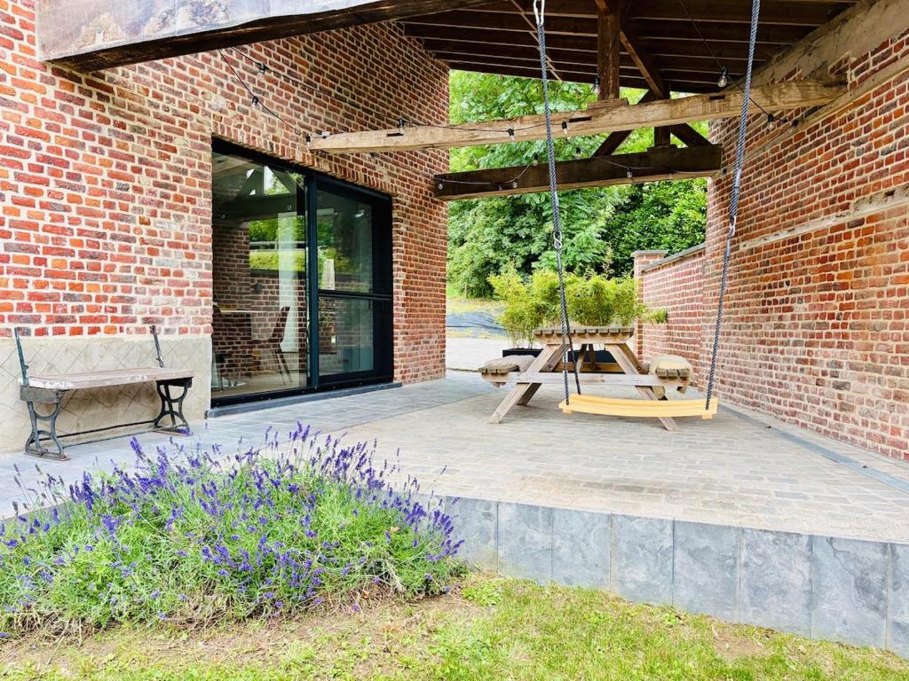 a patio with a swing and a brick wall at Verblijf in het Pajottenland in Gooik