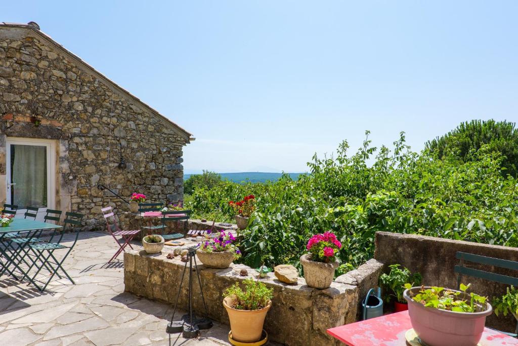 a patio with potted plants and a stone building at Chez Bacchus - Chambres in Gras