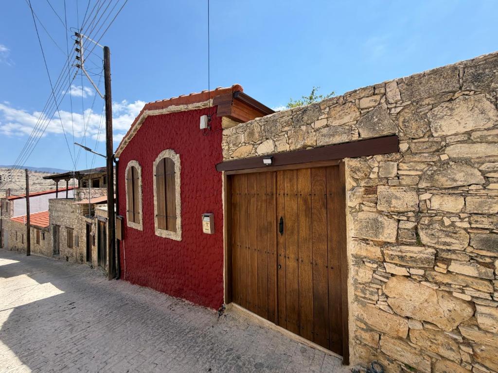 a red building with a wooden door on a street at Melograno Lofou in Lofou