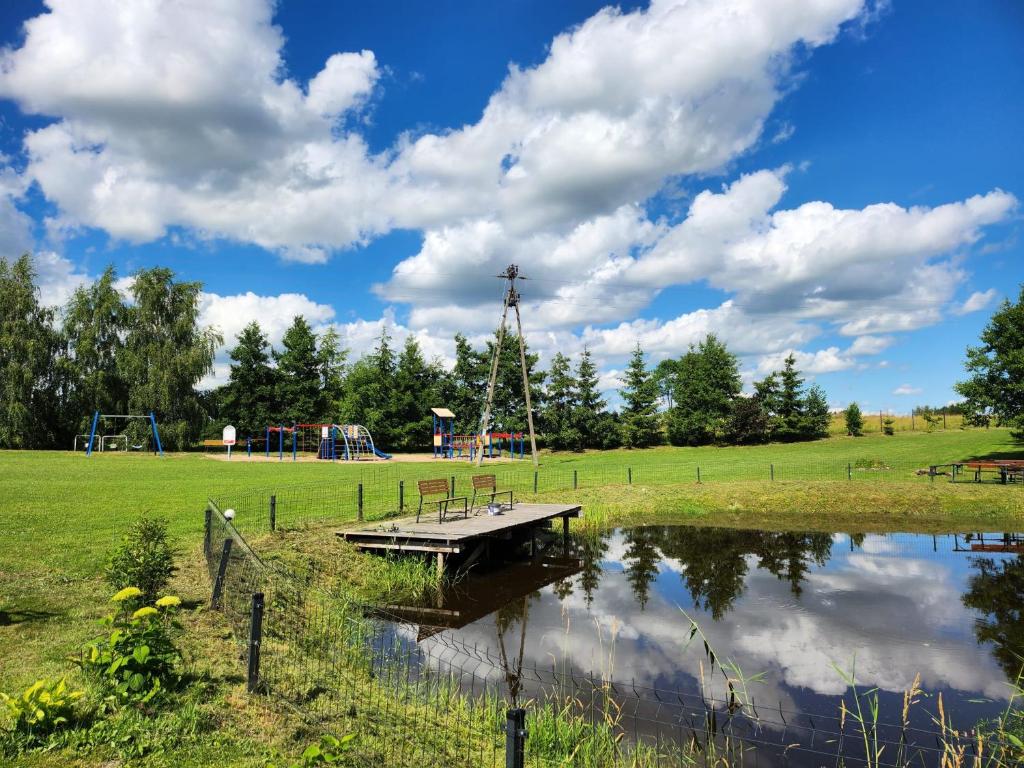 a park with a playground and a bridge over a pond at Domki u Karola Domek nr 1 in Mikołajki