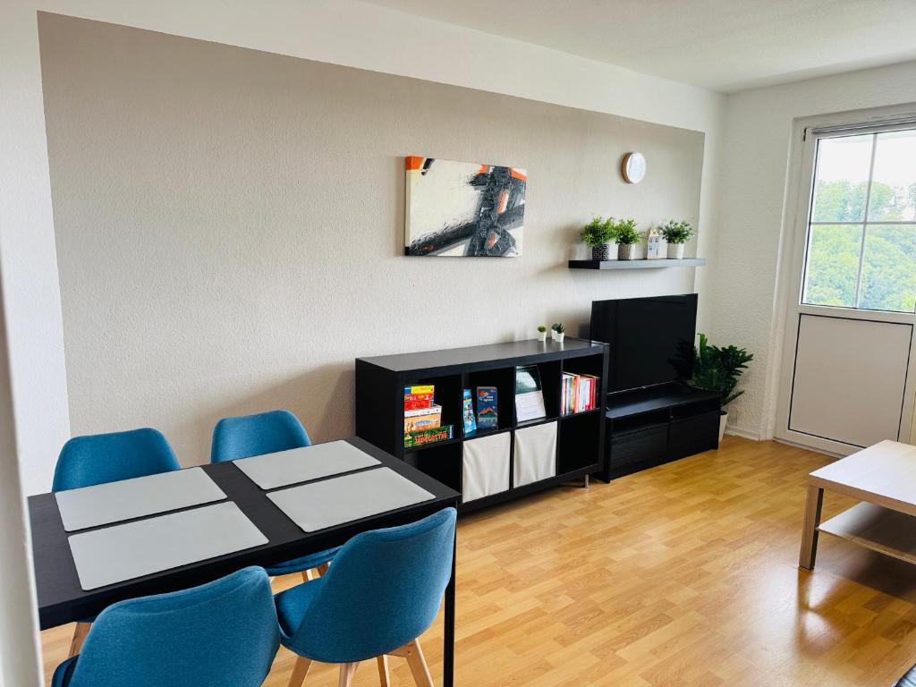a living room with a table and blue chairs at FeWo Einetal 3 im schönen Ostharz in Harzgerode