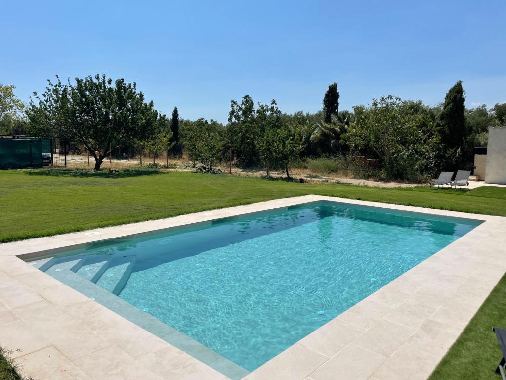 a swimming pool with blue water in a yard at El Loft de Can Padrosa in Riumors