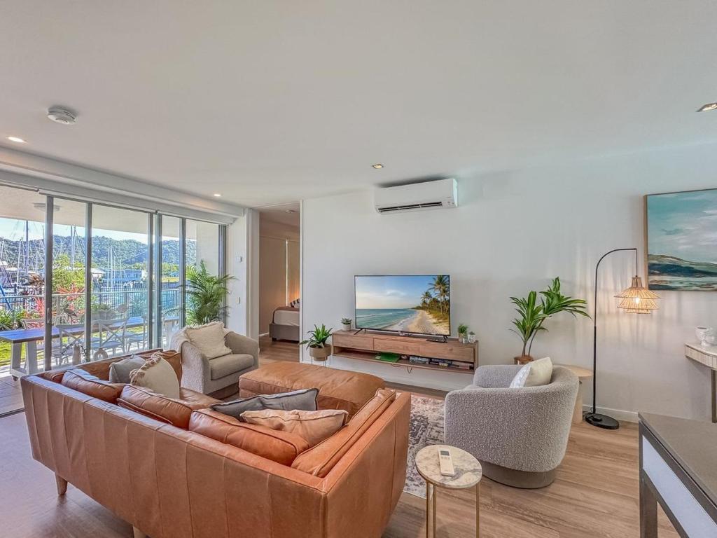 a living room with a brown couch and chairs at Blue on Blue Apartment 1011 in Nelly Bay