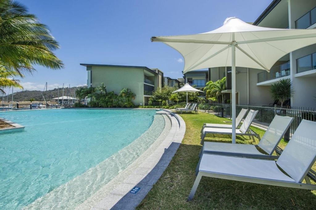 a pool with two lounge chairs and an umbrella at Blue on Blue Apartment 813 in Nelly Bay