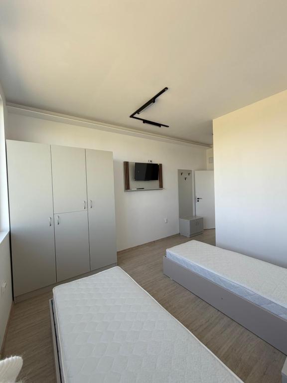 a white room with two beds and a tv at Хостел Дебелт in Debelt
