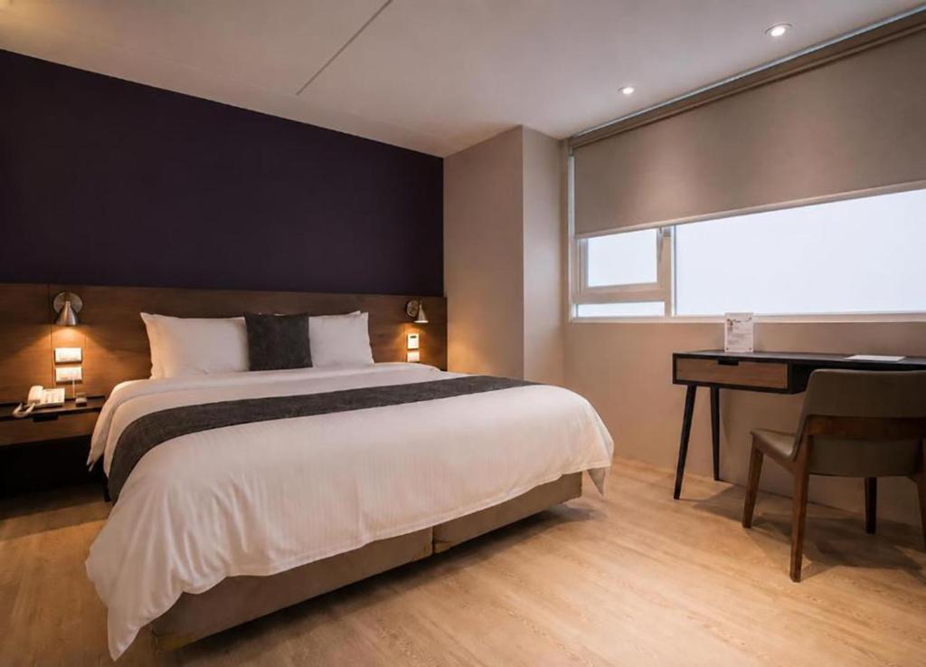 a bedroom with a large bed and a desk and a bed sidx sidx sidx sidx at P&F Hotel in Taichung