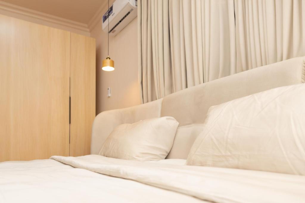 a bedroom with a bed with white sheets and pillows at Hotel Elanza Suites by Signature Stayz Near Delhi Airport in New Delhi