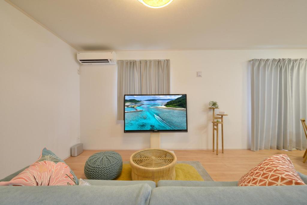 a living room with a couch and a flat screen tv at 北谷町港2 in Chatan
