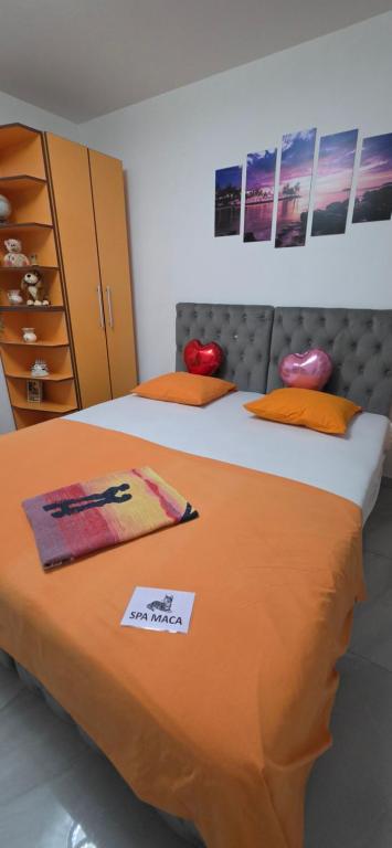 a bedroom with two beds with orange sheets at Maca apartman 23 in Petrovaradin
