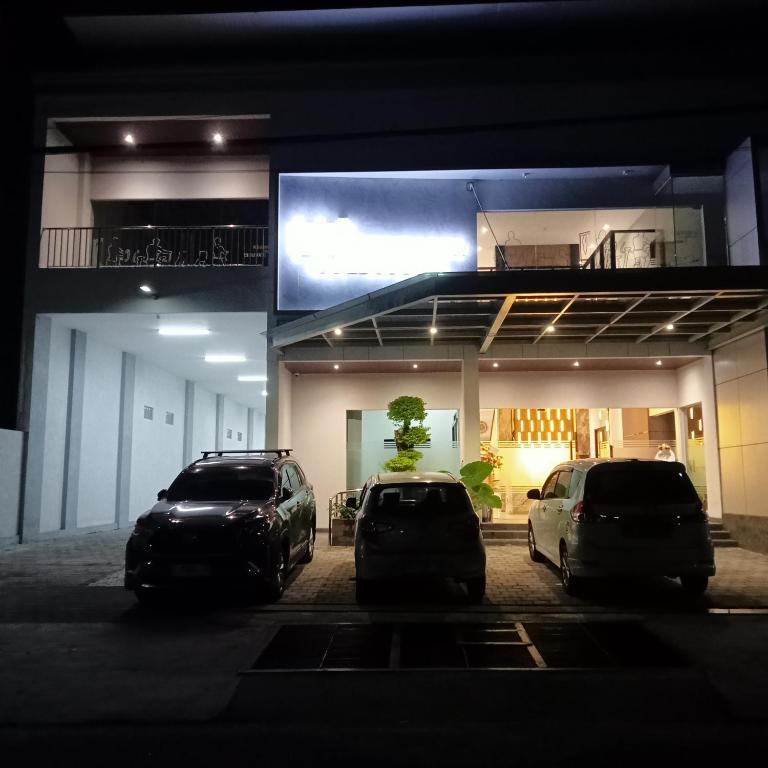two cars parked in front of a building at night at NH Residence Yogyakarta in Ngabean