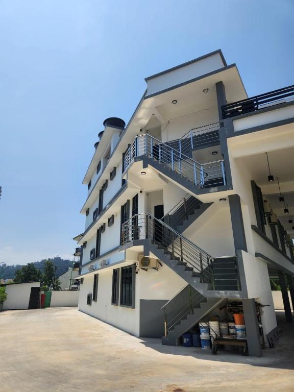 a large white building with stairs in a parking lot at Hotel O Rosegold Garden in Kuantan