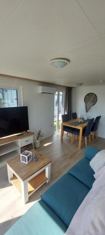 a living room with a bed and a table and a tv at Veluwemeer Lodge in Elburg