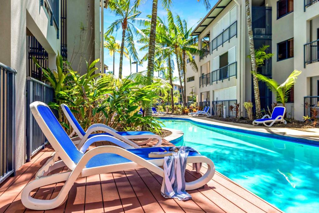 a pair of chairs on a deck next to a swimming pool at Laguna Edge - Swim-Out Studio, near Sea & Dining in Trinity Beach