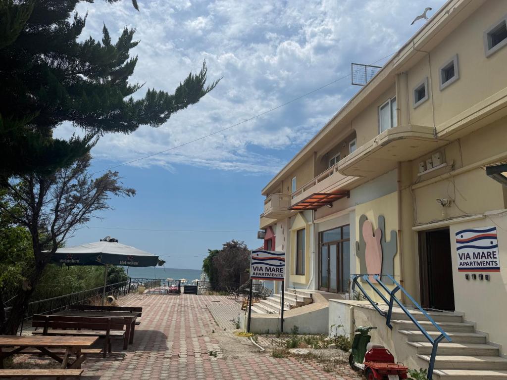 a building with tables and benches next to the ocean at Via Mare Apartments in Alexandroupoli