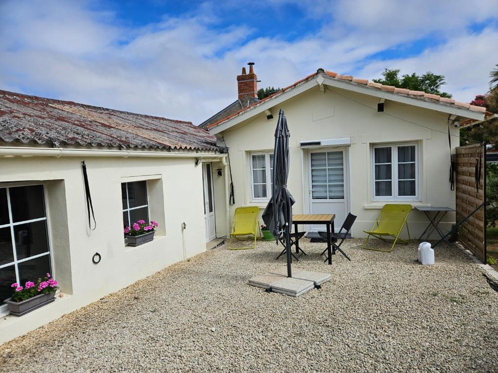 a house with a patio with an umbrella and chairs at Logis du Pey Roux Accueil Marcheurs Vélos in Saint-Jean-de-Monts