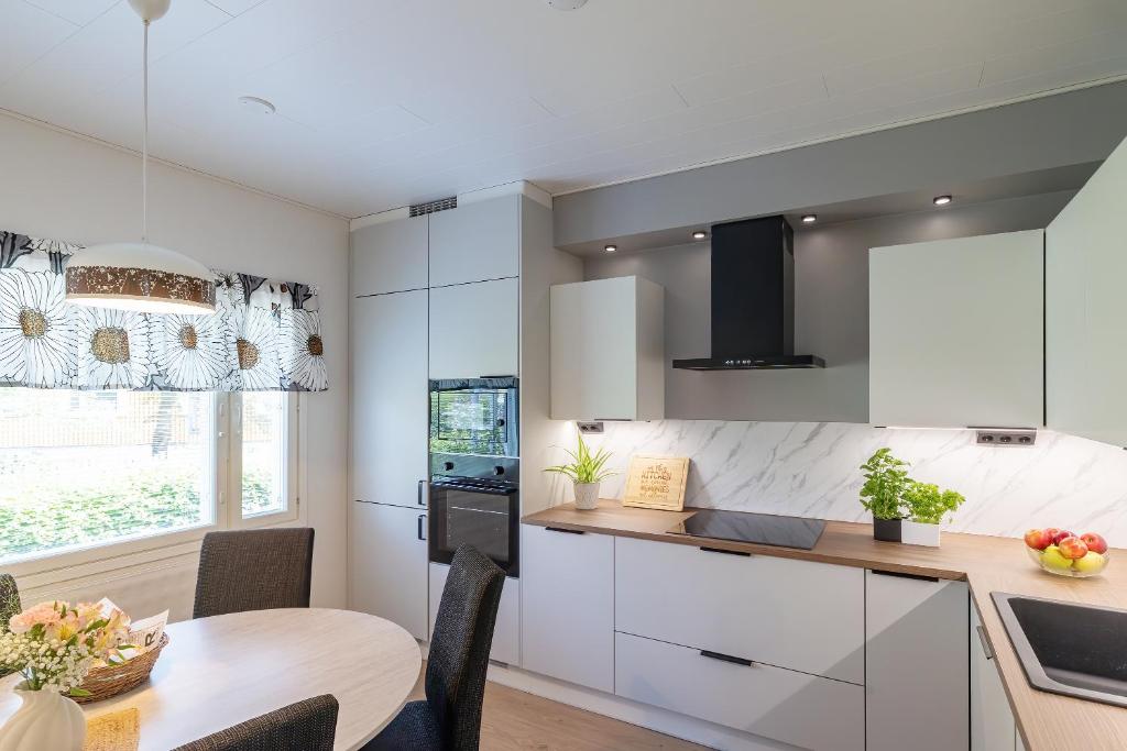 a kitchen with white cabinets and a wooden table at 3 bedrooms house with garden in Rauma