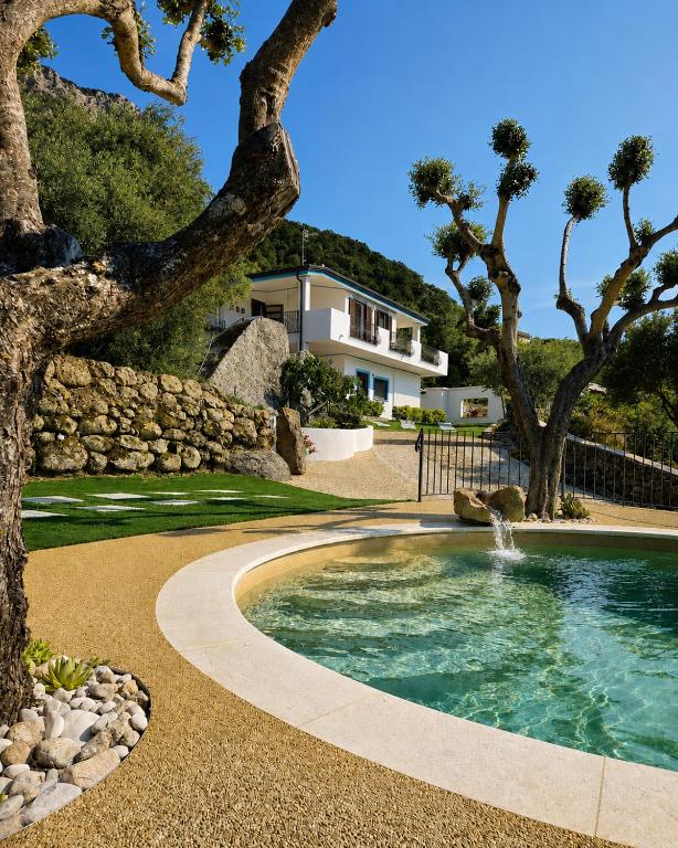 a pool with a waterfall in a yard with trees at B&B Tiscali in Dorgali