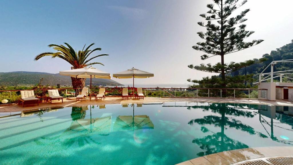 a pool with chairs and umbrellas and a tree at Epidavros Villas - Elia Garden Retreat with Shared Pool in Nea Epidavros