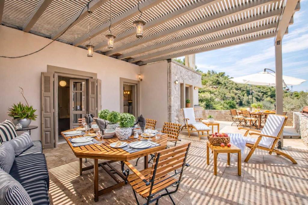 an outdoor patio with a wooden table and chairs at Epidavros Villas, Thymari Garden & Seaview Retreat in Nea Epidavros