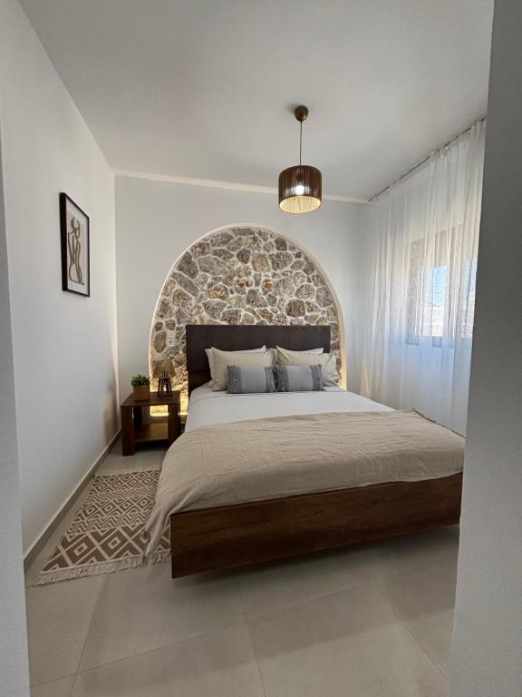 a bedroom with a large bed with a stone wall at Bougainvillea in Asklipiḯon