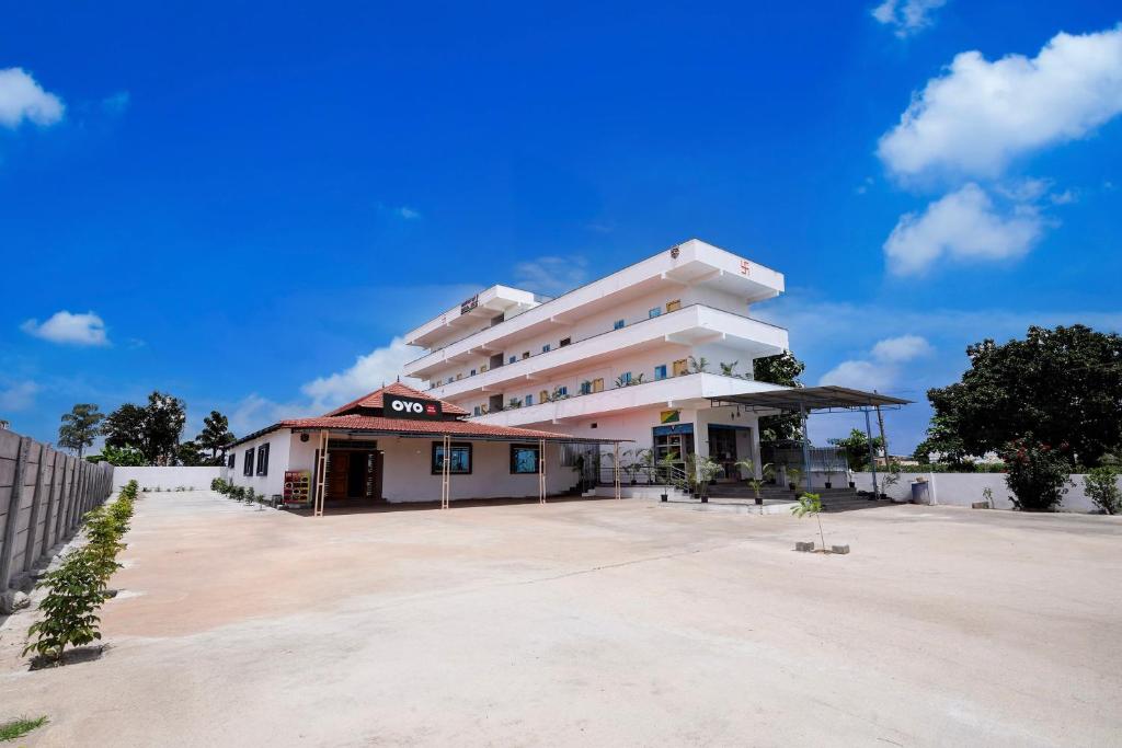 a large white building with a parking lot at Hotel O B.N.R. INN in Bangalore