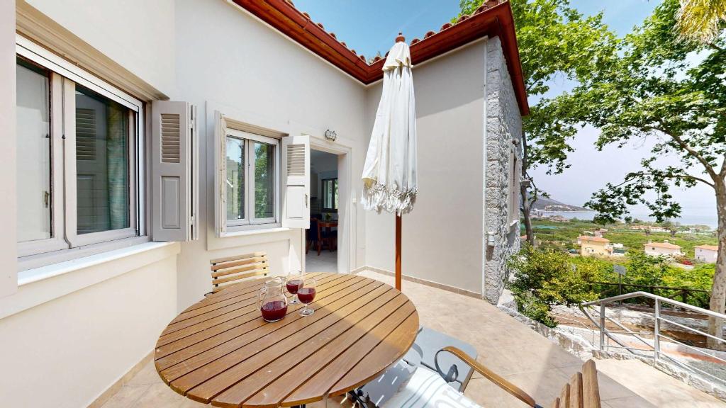 a wooden table on the balcony of a house at Epidavros Villas - Dafni Stone & Garden Retreat in Nea Epidavros
