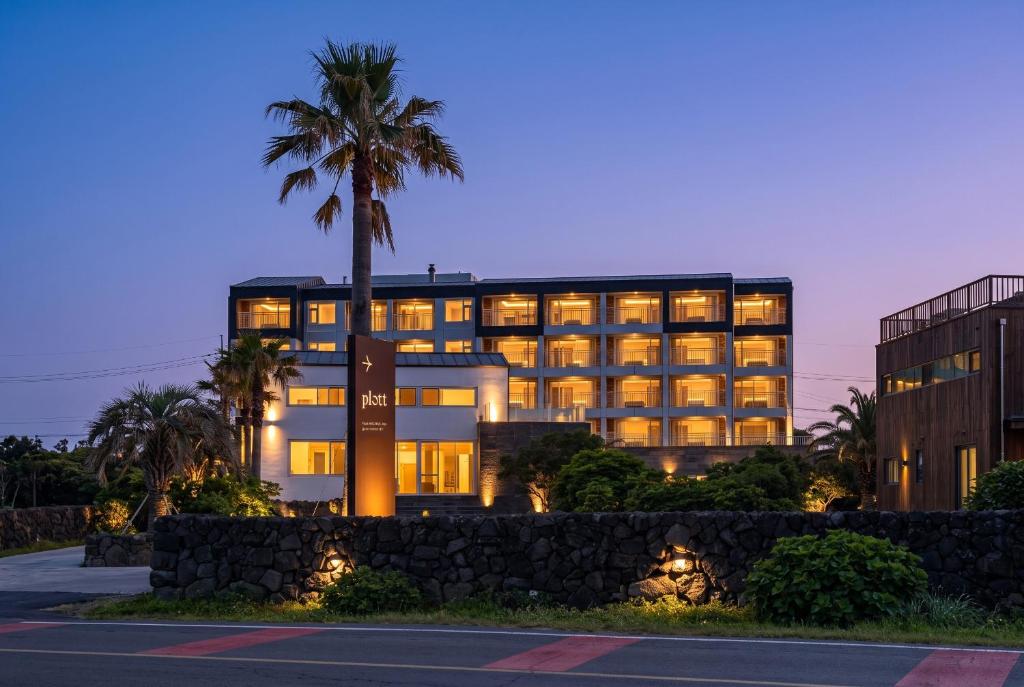 a building with a palm tree in front of it at Plott Archive Jeju in Jeju