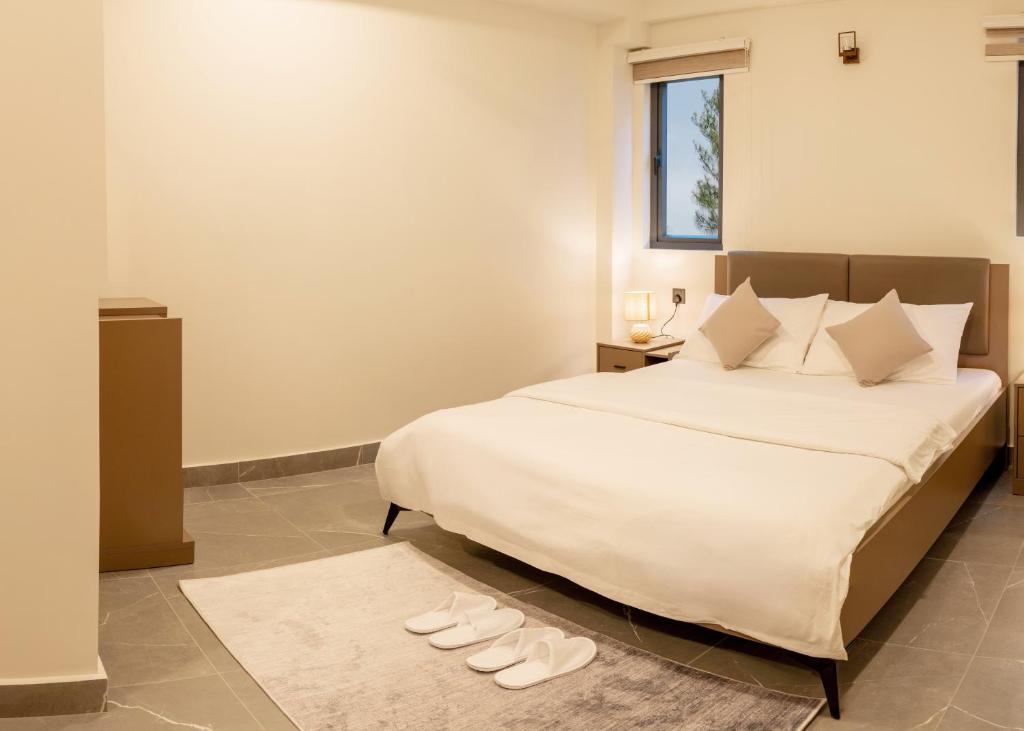 a bedroom with a bed with white sheets and white shoes at Pulsera Beach Residence Maldives by Circles Hospitality in Hulhumale