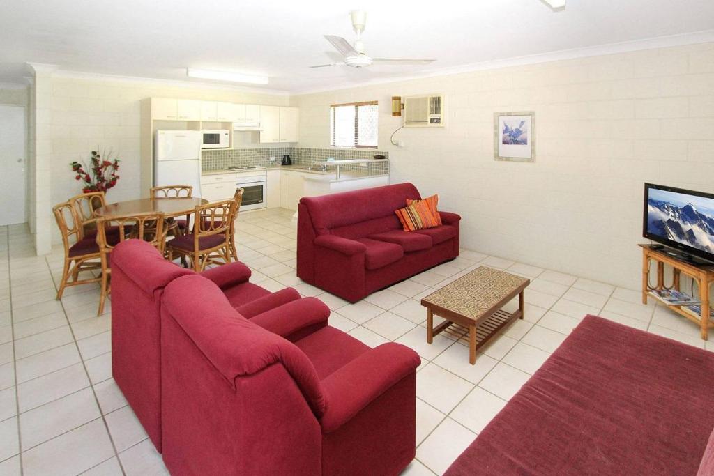 a living room with two red couches and a kitchen at Alma Bay Holiday Unit 4 in Arcadia