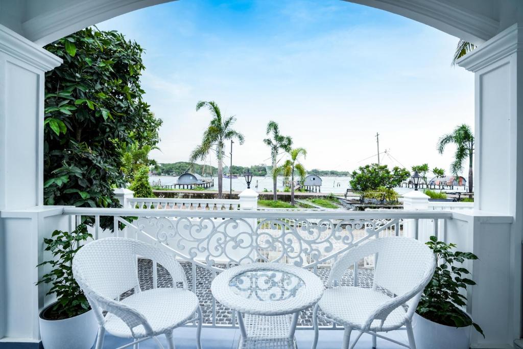a balcony with white chairs and a table at Le Mont Lagoon Home Stay in Cochin