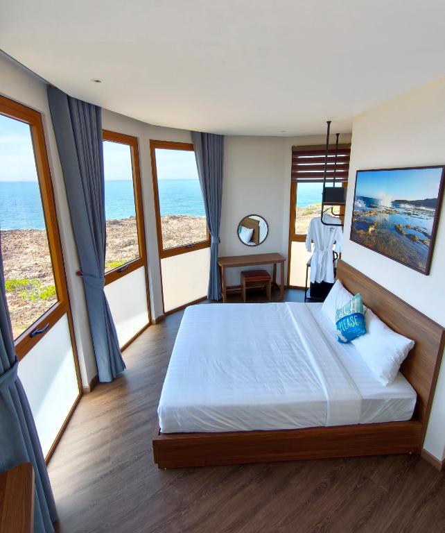 a bedroom with a large bed with large windows at Hon Do Eco Retreat in Mỹ Thanh