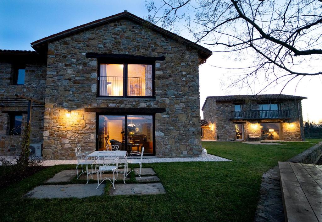 a stone house with a table and chairs in the yard at Dimora Riccio in Dalegna del Collio