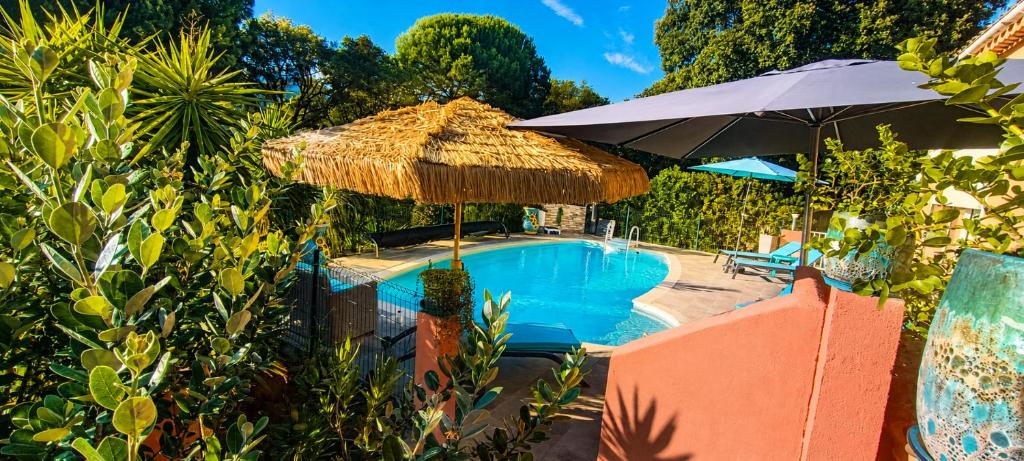 a swimming pool with a straw umbrella next to a swimming pool at chambre d'hôte cosy L'AGHJA in Carbuccia