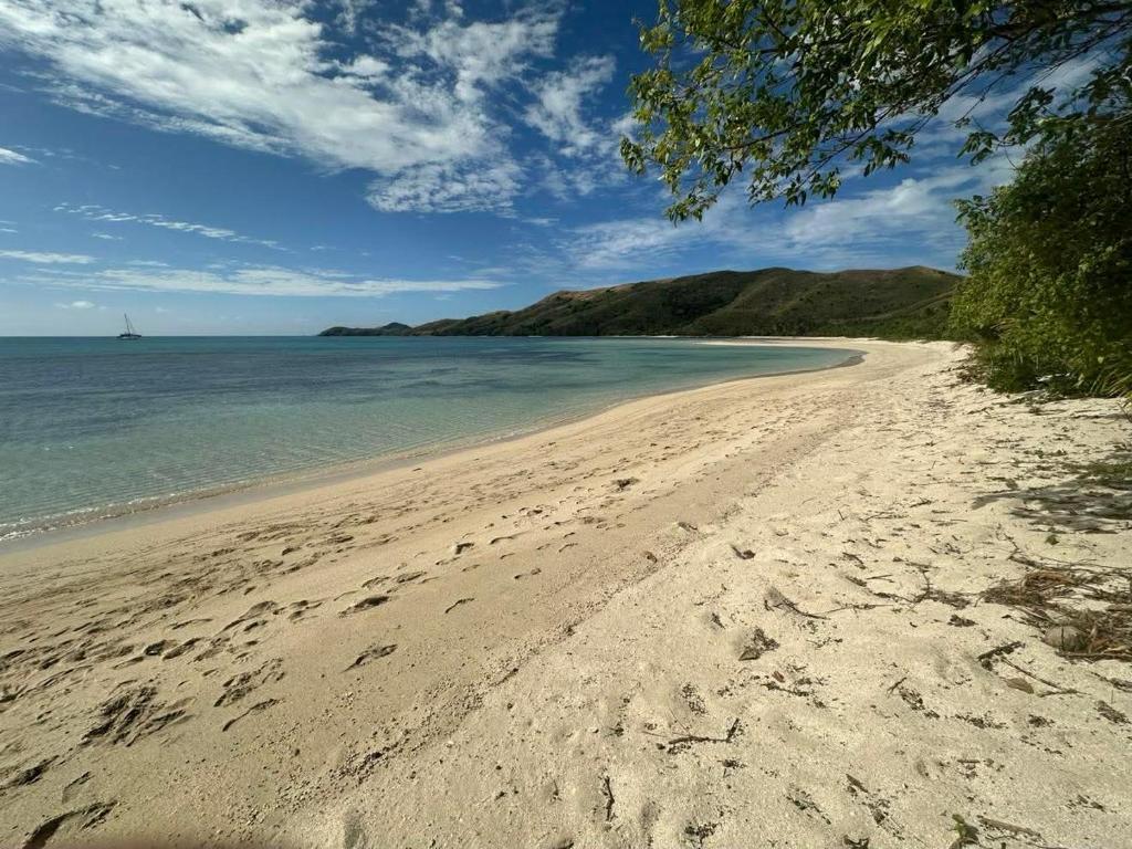 a beach with footprints in the sand and the ocean at Vatudei Homestay - Yasawa Islands in Somosomo