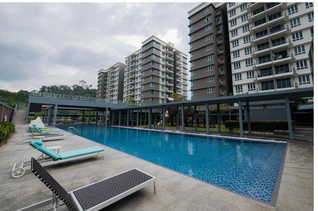 a swimming pool with two chairs and some buildings at Trival Property Homestay Sri Indah Sandakan in Sandakan