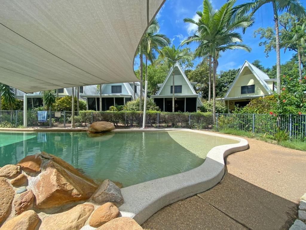 a swimming pool in front of a house at Canopy Chalet 4 in Nelly Bay