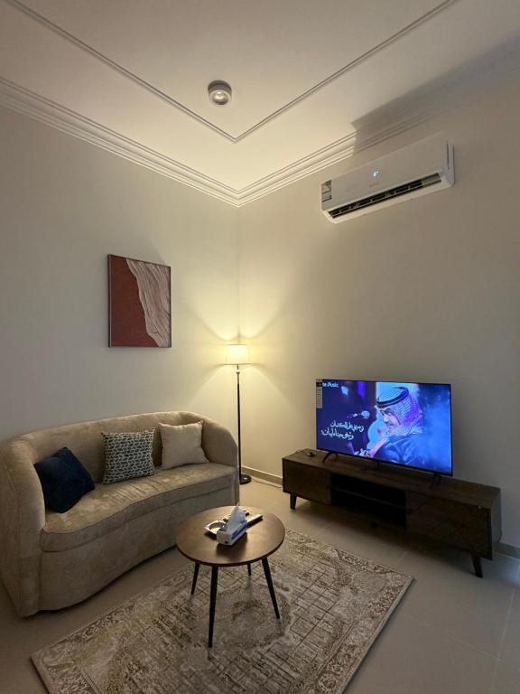 a living room with a couch and a flat screen tv at شادن للوحدات السكنية in Qufār