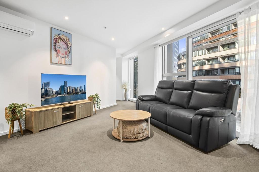 a living room with a couch and a tv at Stylish 2-Bed Apartment by 888 Collins in Melbourne