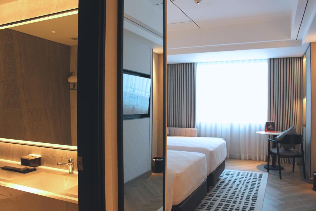 a hotel room with a bed and a bathroom at Hotel Ciputra Cibubur managed by Swiss-Belhotel International in Cibubur