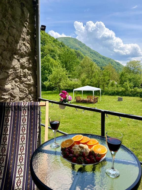 a table with a bowl of fruit and two glasses of wine at Mtisani in Roshka